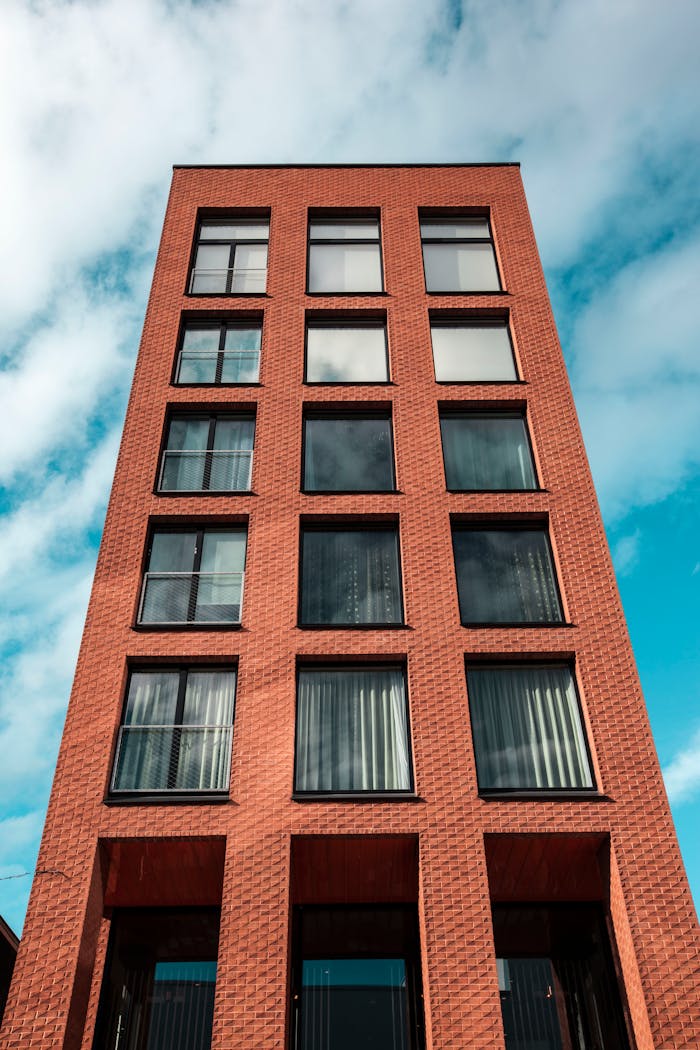 services-04 Red-brick modern building against a vibrant blue sky and clouds.